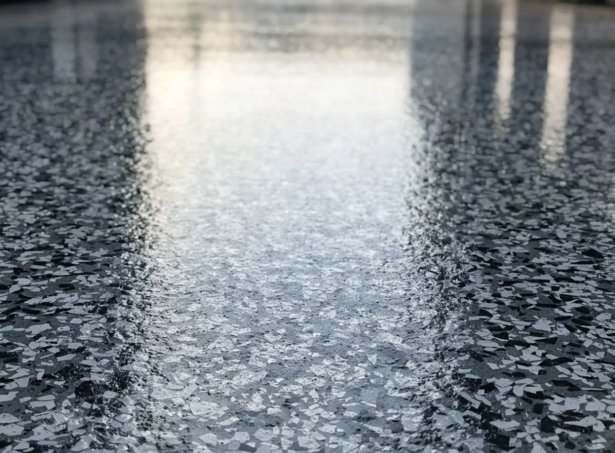 Close-up of a grey and white flake garage floor coating with a gloss topcoat